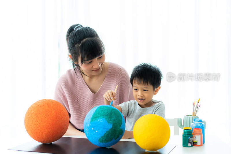 亚洲学前班男孩与母亲画月亮在家里学习关于太阳系，在家教育和远程学习。