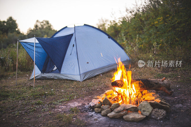 早上的营地，蓝色的帐篷和燃烧的火坑