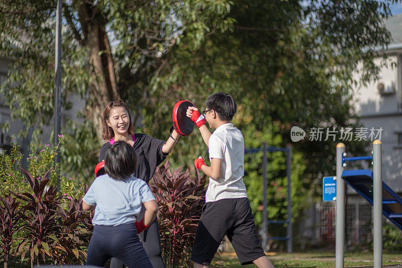 亚洲华人妈妈和孩子们在公园里玩得很开心。他们在训练跆拳道。泰拳，武术