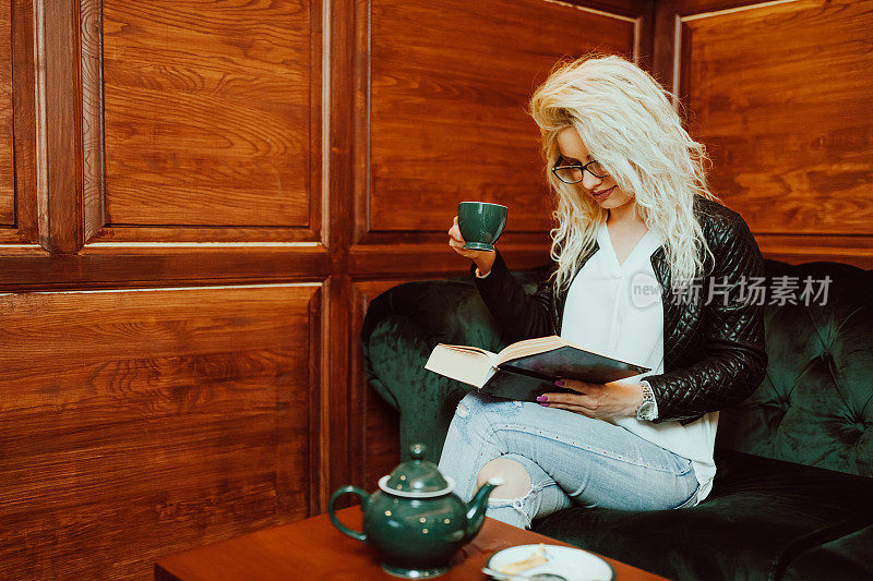 年轻女子一边看书一边喝茶