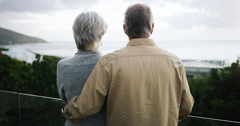 一对快乐的老年夫妇站在阳台上看海景的后视镜