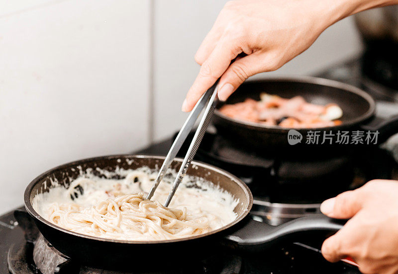 奶油干酪意面是在厨房背景的煎锅里煮的