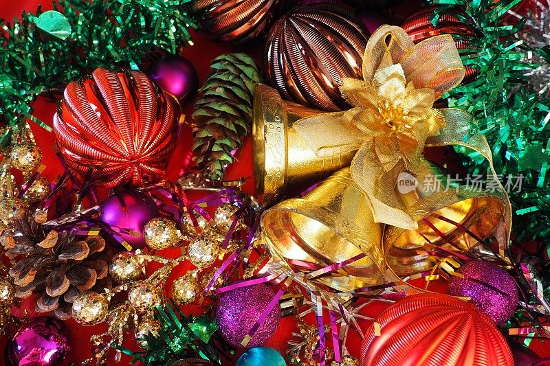 圣诞背景用圣诞装饰物，节日球、铃铛、蝴蝶结、冷杉锥、圣诞树雨。新年快乐，圣诞快乐。红色，棕色，条纹，绿色，金色，紫色，五颜六色的装饰