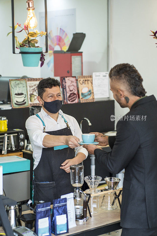 一家咖啡工厂的拉丁裔雇员站在为顾客准备咖啡的酒吧里