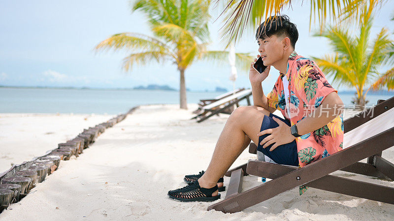 亚洲商人与商业伙伴交谈，在度假海滩椅上