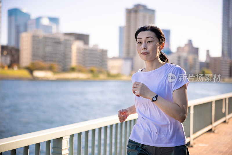 一个女人在城市的河边奔跑