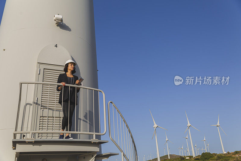 女商人正在用数码平板电脑检查风力涡轮机的可再生能源。