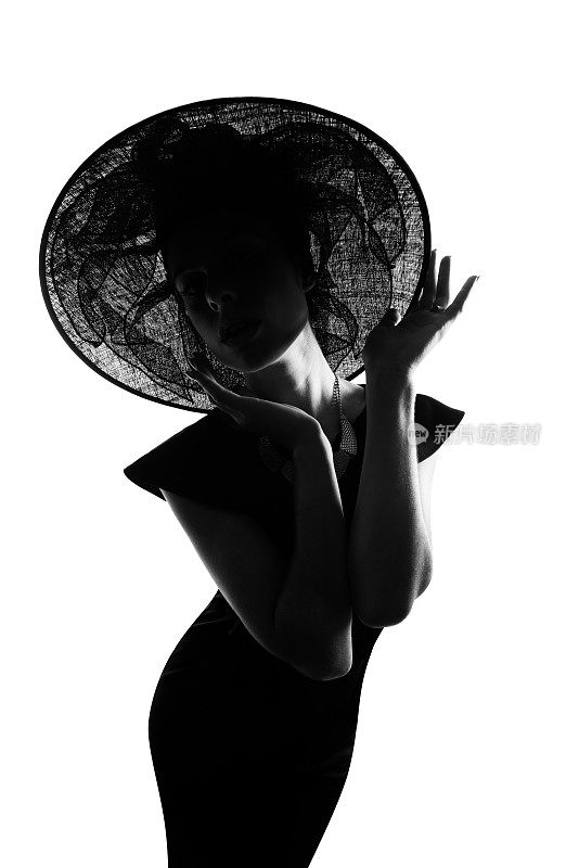 摄影工作室拍摄的一个时尚的女人剪影，在白色的背景下戴着宽边帽子
