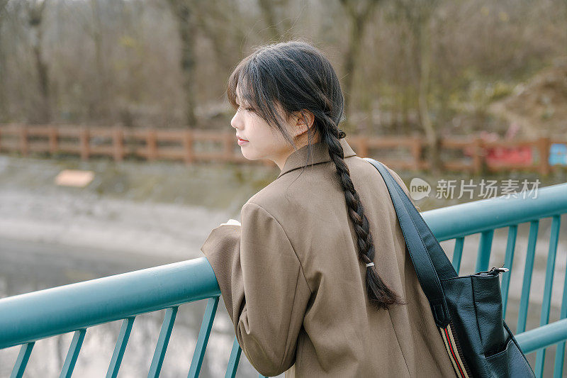 年轻的亚洲女孩背着包在桥上