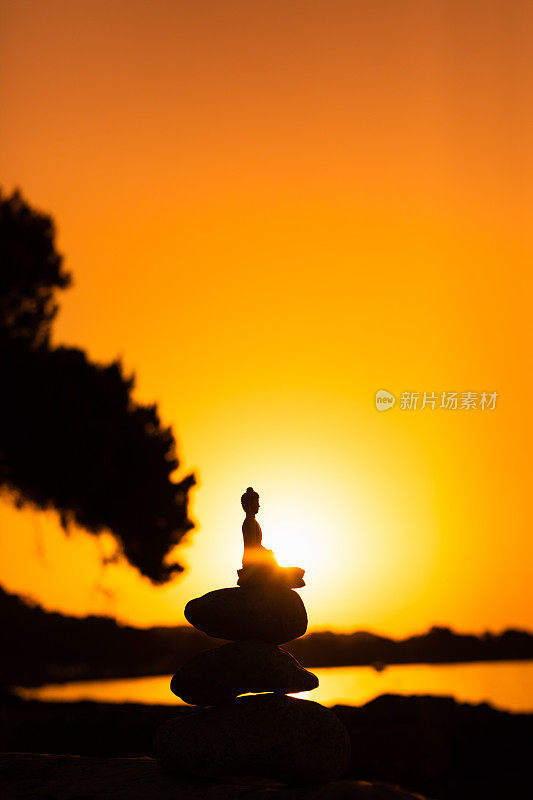 在真正的日出中，佛陀的剪影坐在堆积的禅石上