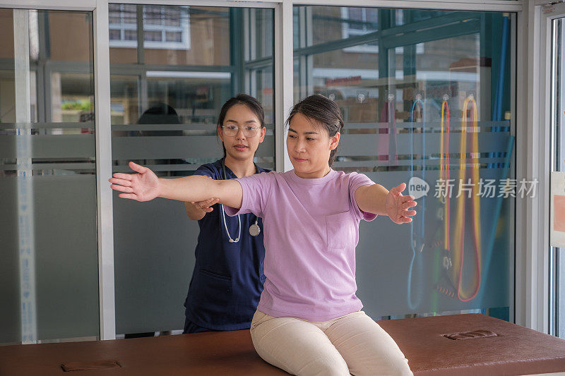 与女医生或物理治疗师进行脊椎按摩手臂和肩膀调整的亚洲女性患者的医疗访问