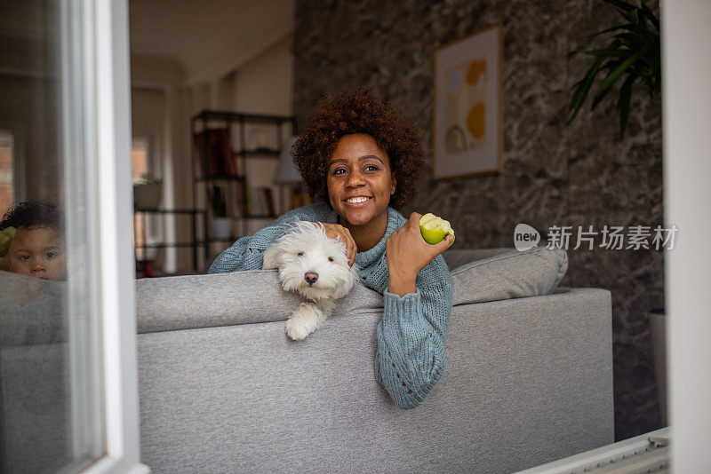 黑人和她的狗坐在沙发上吃苹果