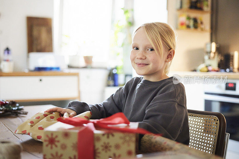 可爱的女孩在家里包装圣诞礼物
