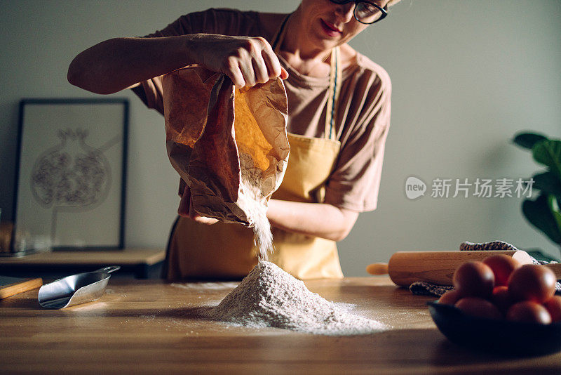 在家里厨房里，一名女子在厨房的工作台上倒面粉