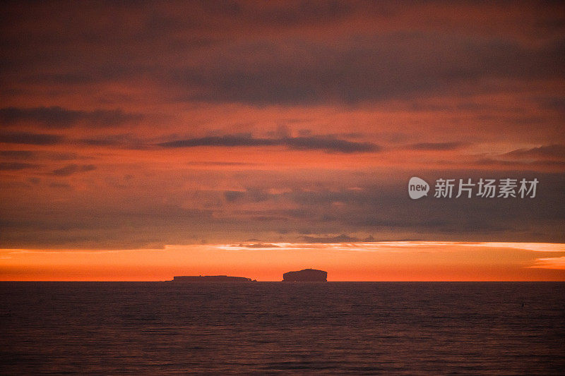 午夜日落的海洋与两个岛屿的剪影在夏天的冰岛北部