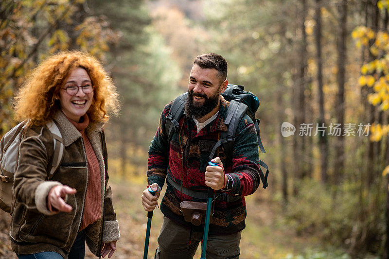 一对快乐的年轻夫妇正在森林里徒步旅行