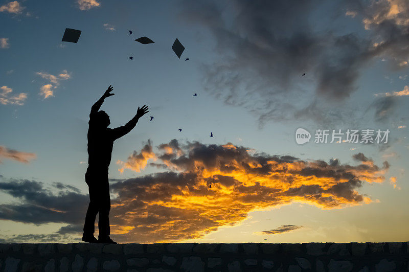 一个孤独的男人在日落时举起双手的剪影