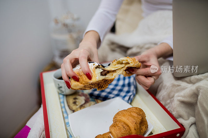 女人在床上吃早餐。光窗口