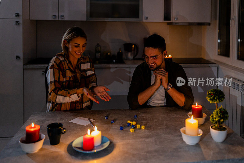 一对年轻夫妇在家里遭遇电力危机，正在玩骰子游戏。