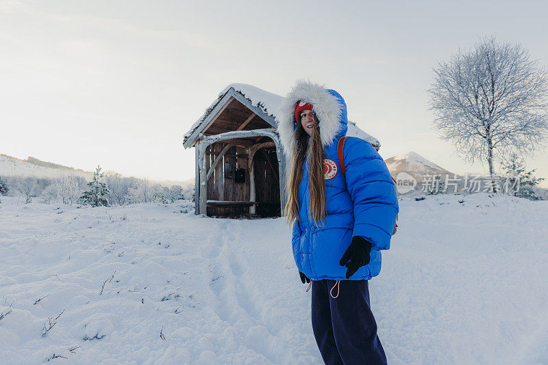 挪威，一名女子走在通往收容所的雪道上，凝视着寒冷的冬日