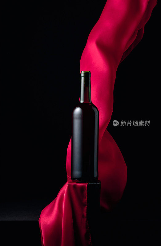 一瓶红酒和飘动的红布。