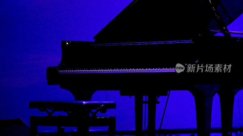 一架大钢琴在演出前放在灯光昏暗的舞台上