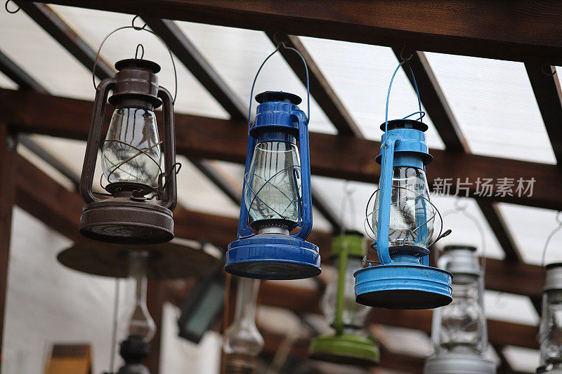 三盏传统煤油灯悬挂在一家古董店的木质天花板下。