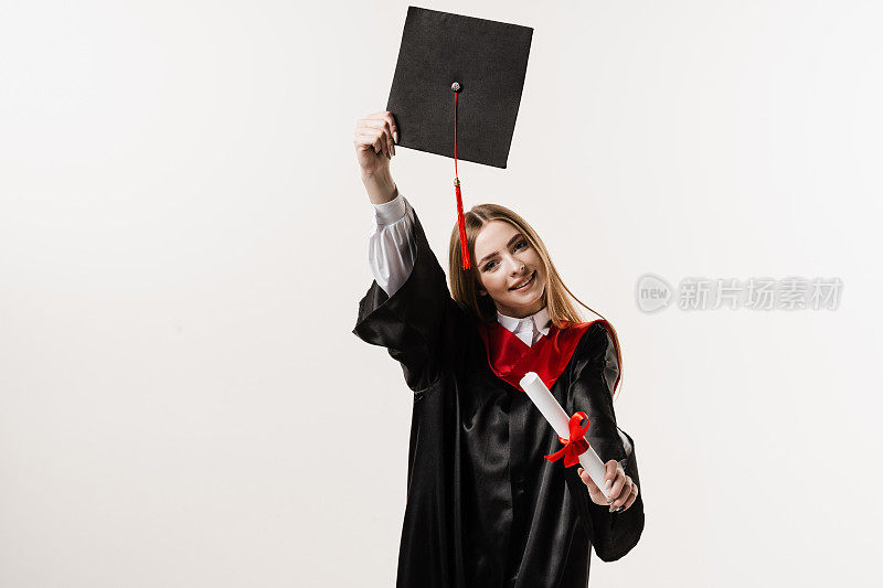毕业女孩高中毕业，庆祝学业成就。硕士学位证书在手。身着黑色毕业服，头戴黑色毕业帽的快乐学生在白色背景下微笑。