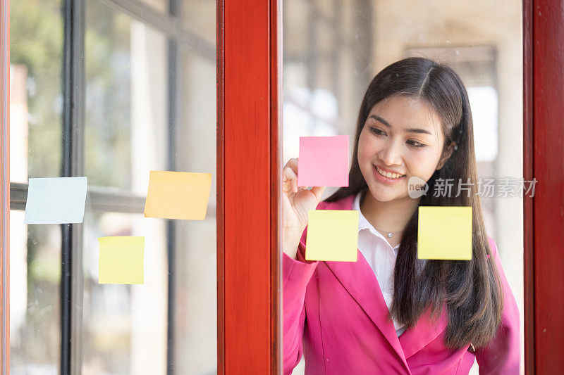 亚洲商业女性头脑风暴和工作在现代办公室工作场所与便利贴在窗口