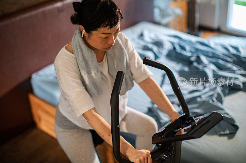 一名年轻的日本女子在卧室的室内自行车上锻炼
