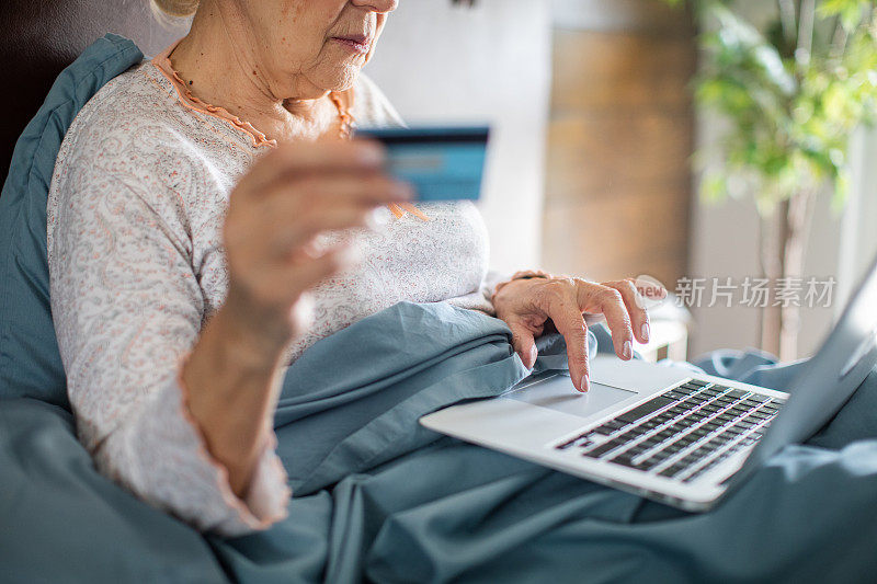 老女人在卧室用笔记本电脑网购