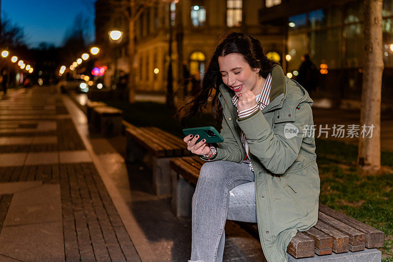 年轻女子在晚上用手机看游戏时沉浸在游戏中