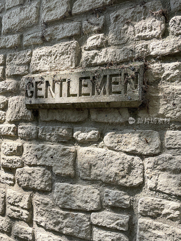 砖墙上有“绅士”字样的水泥信息标识特写，男厕位置信息标识(绅士)