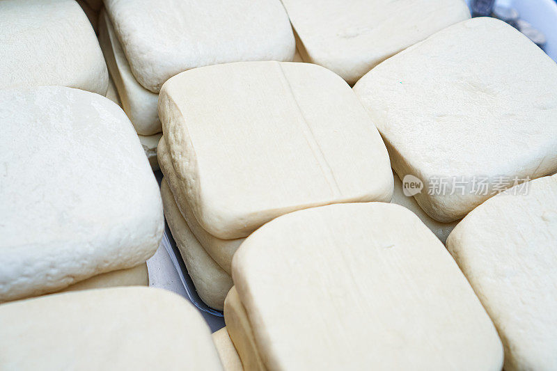在一个新鲜的蔬菜市场，白色的豆腐块排列在桌子上。