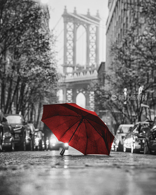 在一个雾蒙蒙的日子里，打着红伞，从两栋砖砌建筑围成的狭窄巷子里看曼哈顿大桥。