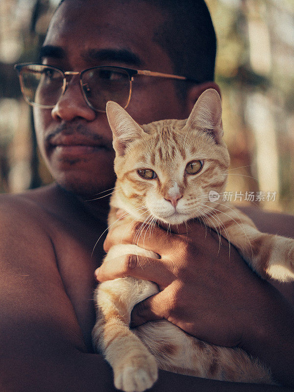 棕色的男人和橙色的猫在玩