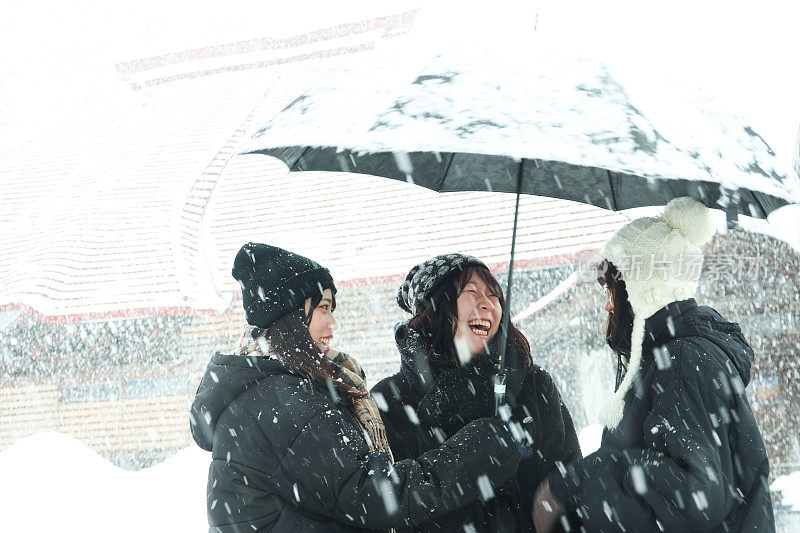 年轻的妇女在街上享受下雪