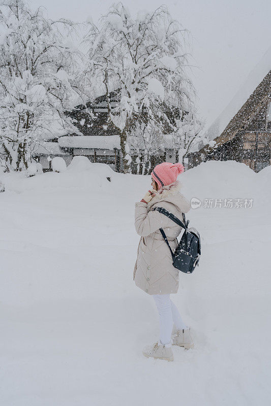 美丽的女游客享受他们的旅行白川古村在日本的冬天厚雪