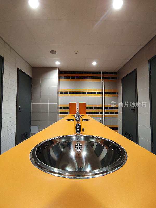 公共厕所的金属水槽和带光电池的水龙头，非接触式。