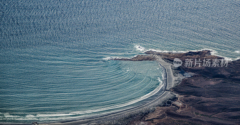 几组太平洋海浪撞击一小块陆地，造成波浪弯曲。下加利福尼亚南部，墨西哥。波变浅。