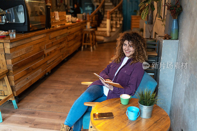 年轻女子在咖啡馆里一边喝咖啡一边看书