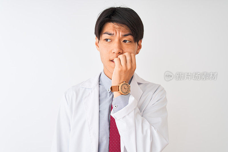 一名中国科学家戴着领带，穿着外套，站在孤立的白色背景下，看起来紧张而紧张，双手放在嘴上咬指甲。焦虑的问题。