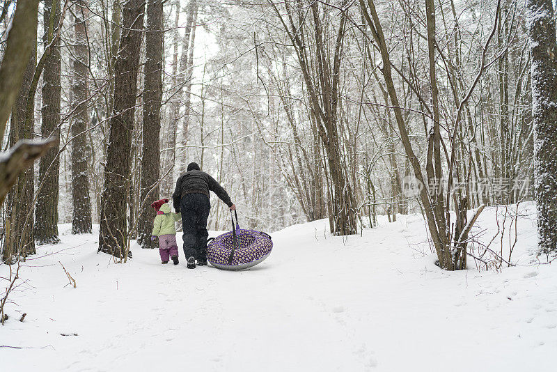70岁的老人，爷爷和2岁的孙女，正在森林里爬山，带着一个雪管准备下一站。