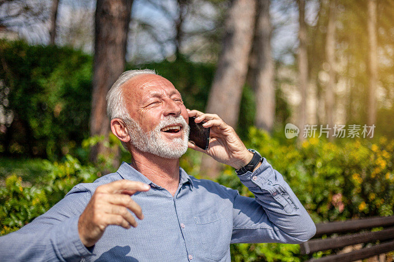一位老人在公园里使用智能手机
