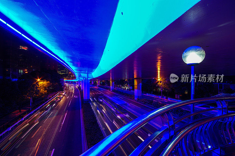在中国上海的延安高架路上，在繁忙的交通中，汽车和公共汽车的轨迹被蓝色的霓虹灯照亮