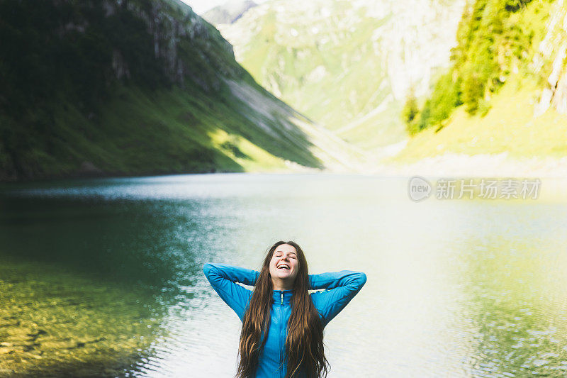 年轻女子享受夏天阳光明媚的早晨在山上的湖在瑞士阿尔卑斯山