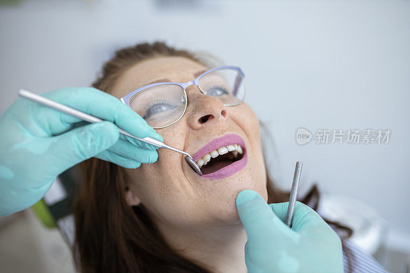 牙医使用挖掘机镰刀探针进行牙科检查