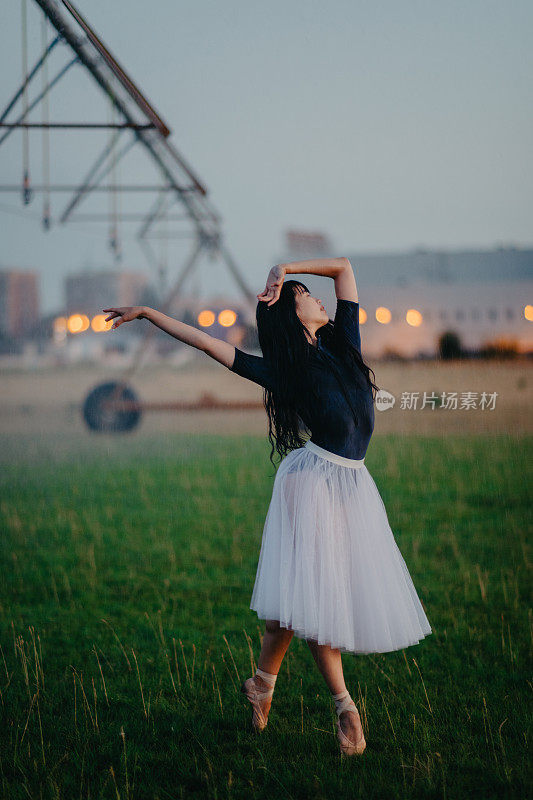 一名芭蕾舞演员在农田里的喷雾器旁跳舞。