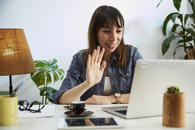 年轻女子在她的家庭办公室里用电脑聊天