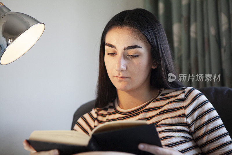 一个年轻女子在台灯下看书